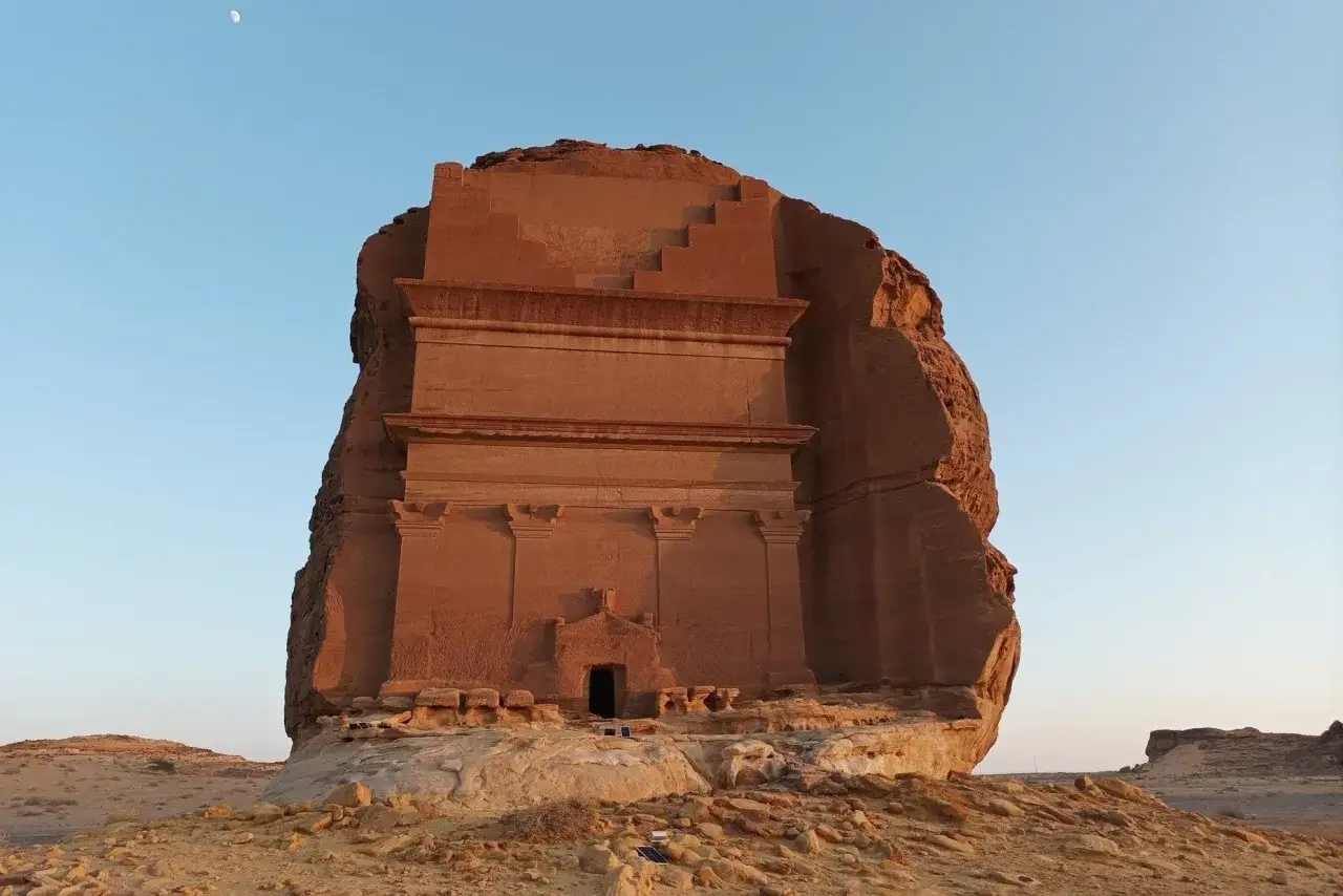 Grobowiec w Al-Churajbie, jeden z cudów, co zobaczyć w Arabii Saudyjskiej. Monumentalna budowla wykuta w skale, z widocznym księżycem na niebie.