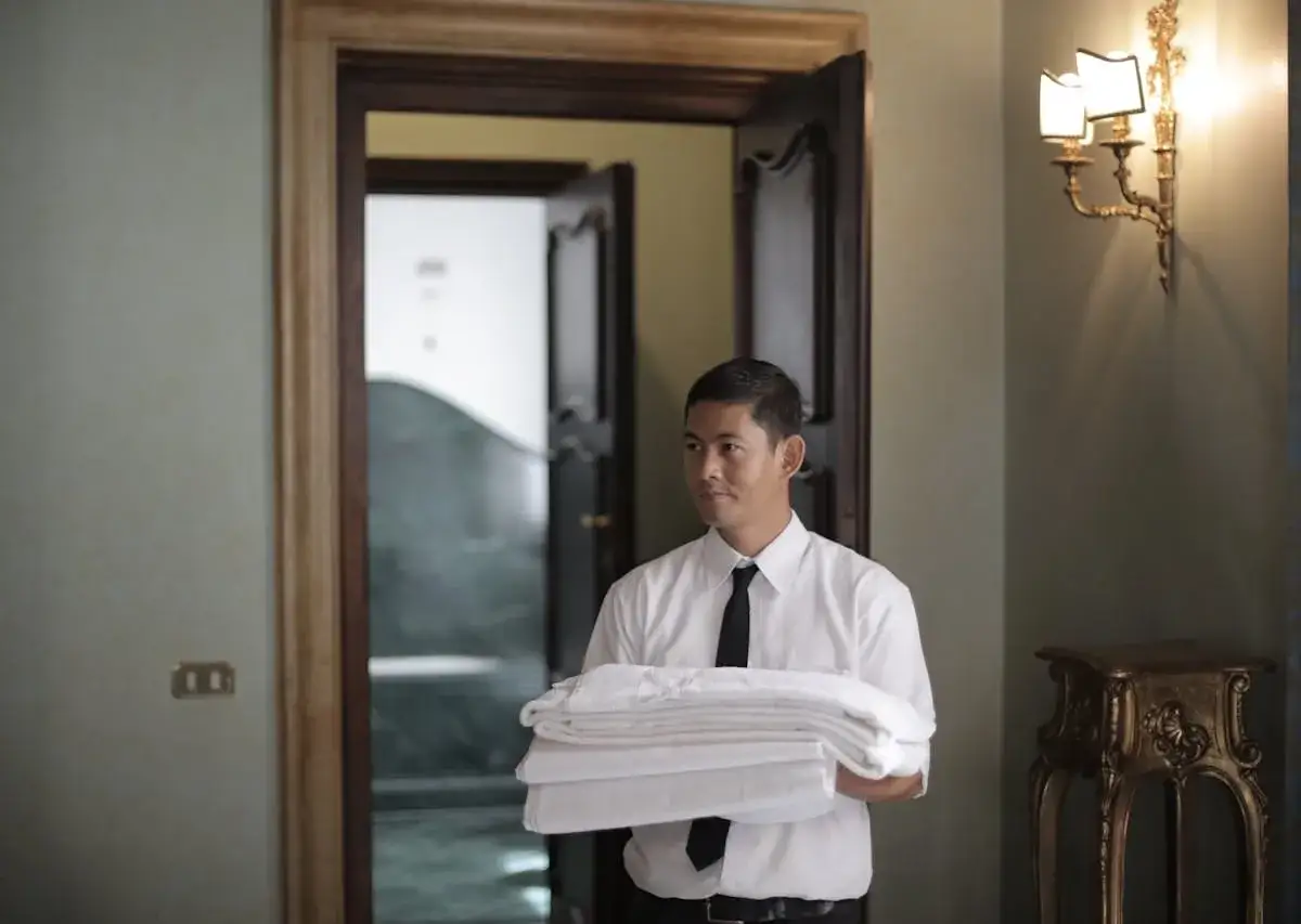 Hotelowy pracownik z ręcznikami. Dowiedz się, jak zostawić napiwek w hotelu, doceniając jego pracę.