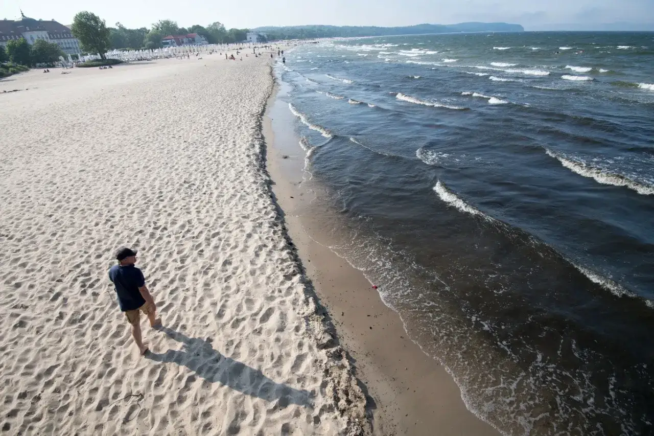 Spacer po plaży, gdy jest najwięcej jodu nad morzem. W tle widać budynki i ludzi.