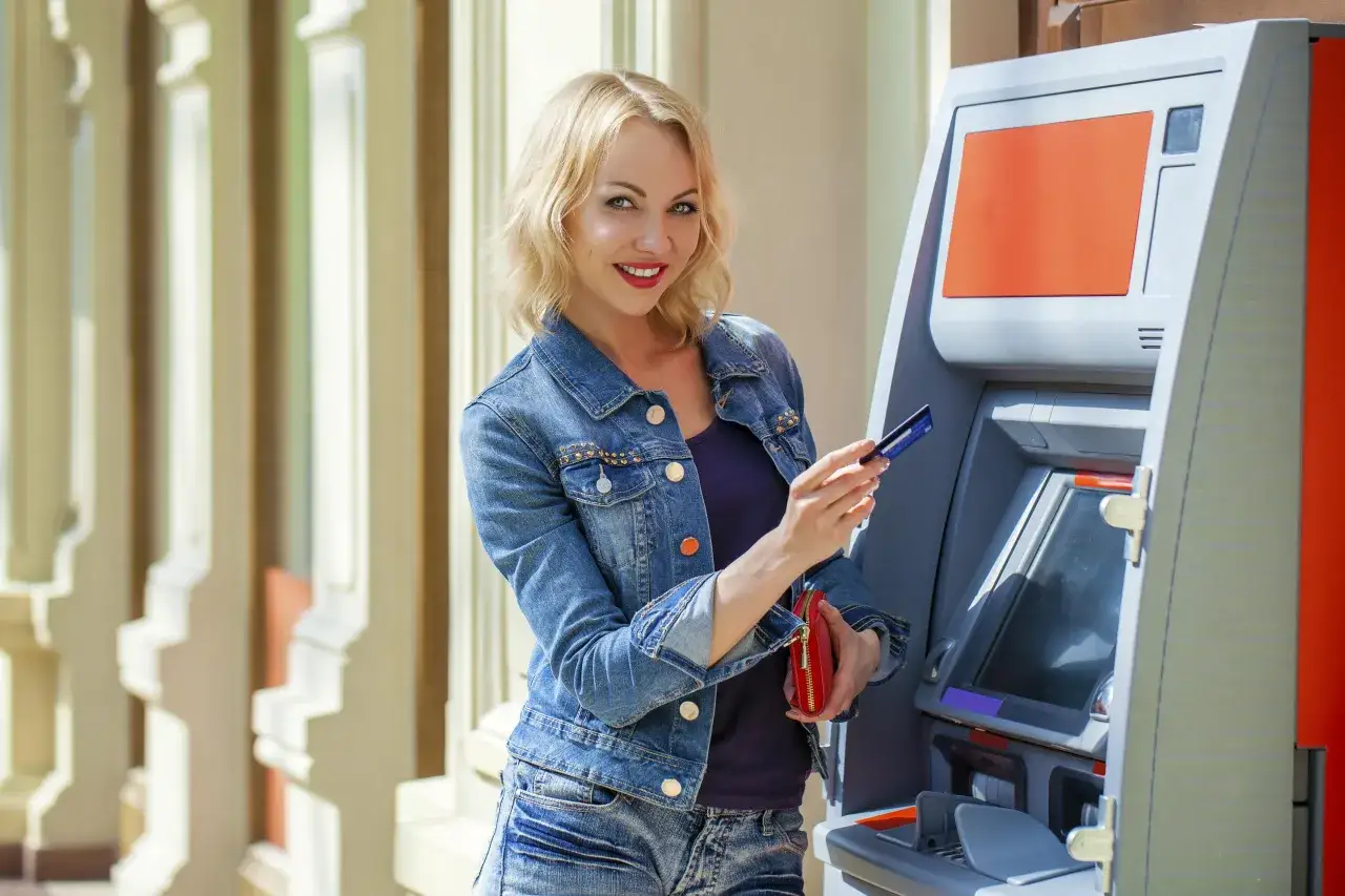 Kobieta z kartą Visa przy bankomacie. Węgry akceptują płatności kartą Visa, więc bez problemu zapłacisz nią za zakupy.