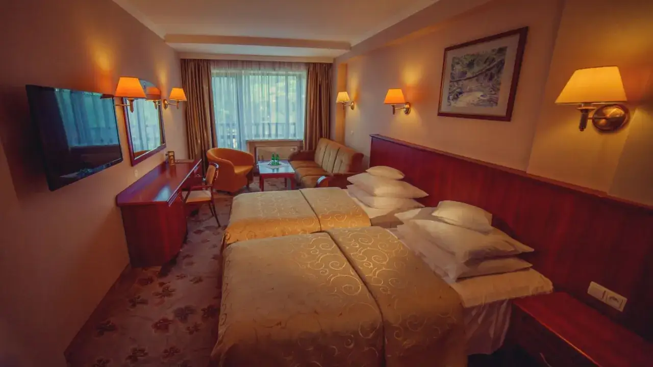 Pokój hotelowy z dwoma łóżkami, kanapą i fotelem. Ile pokoi ma hotel Gołębiewski w Wiśle? Tyle, ile potrzeba, by pomieścić wszystkich gości!