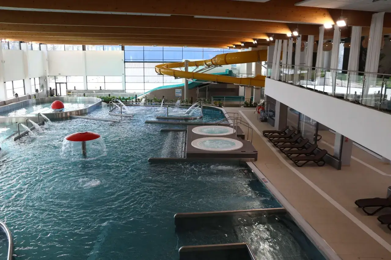 Wodne atrakcje w parku wodnym Częstochowa: baseny, jacuzzi, zjeżdżalnia i czerwone grzybki wodne.