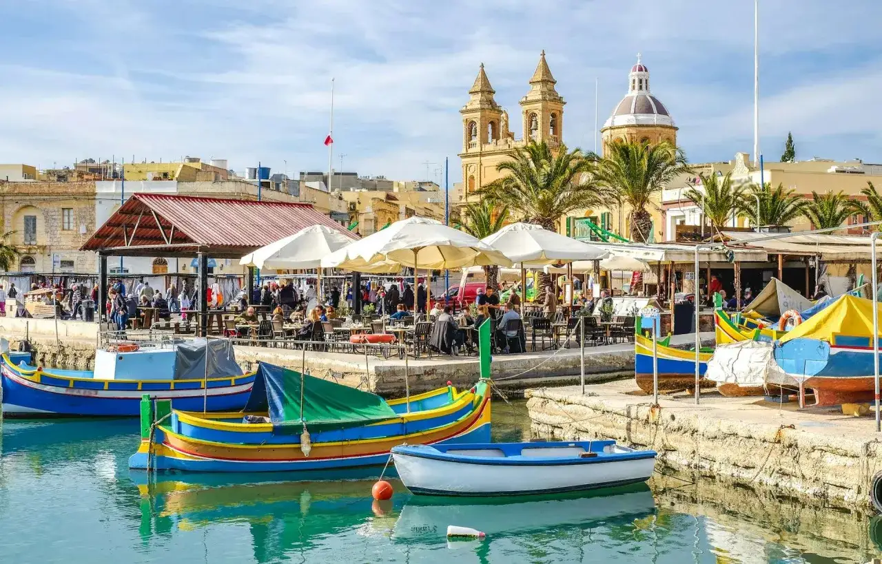 Malta w lutym: kolorowe łodzie, kawiarnie na nabrzeżu i kościoły. Temperatura sprzyja spacerom.