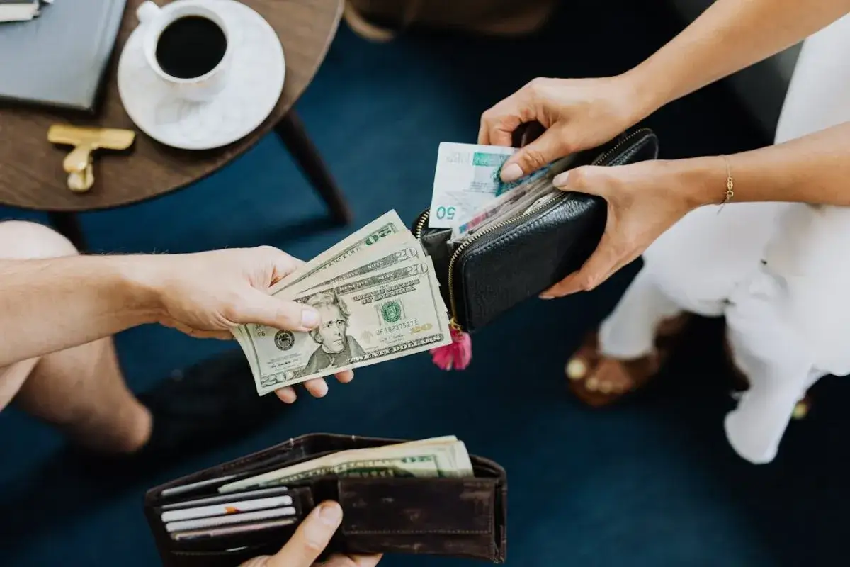 Dwie osoby wymieniają się pieniędzmi. Jedna trzyma dolary, druga wkłada do portfela banknoty. Czy w Turcji można płacić dolarami?