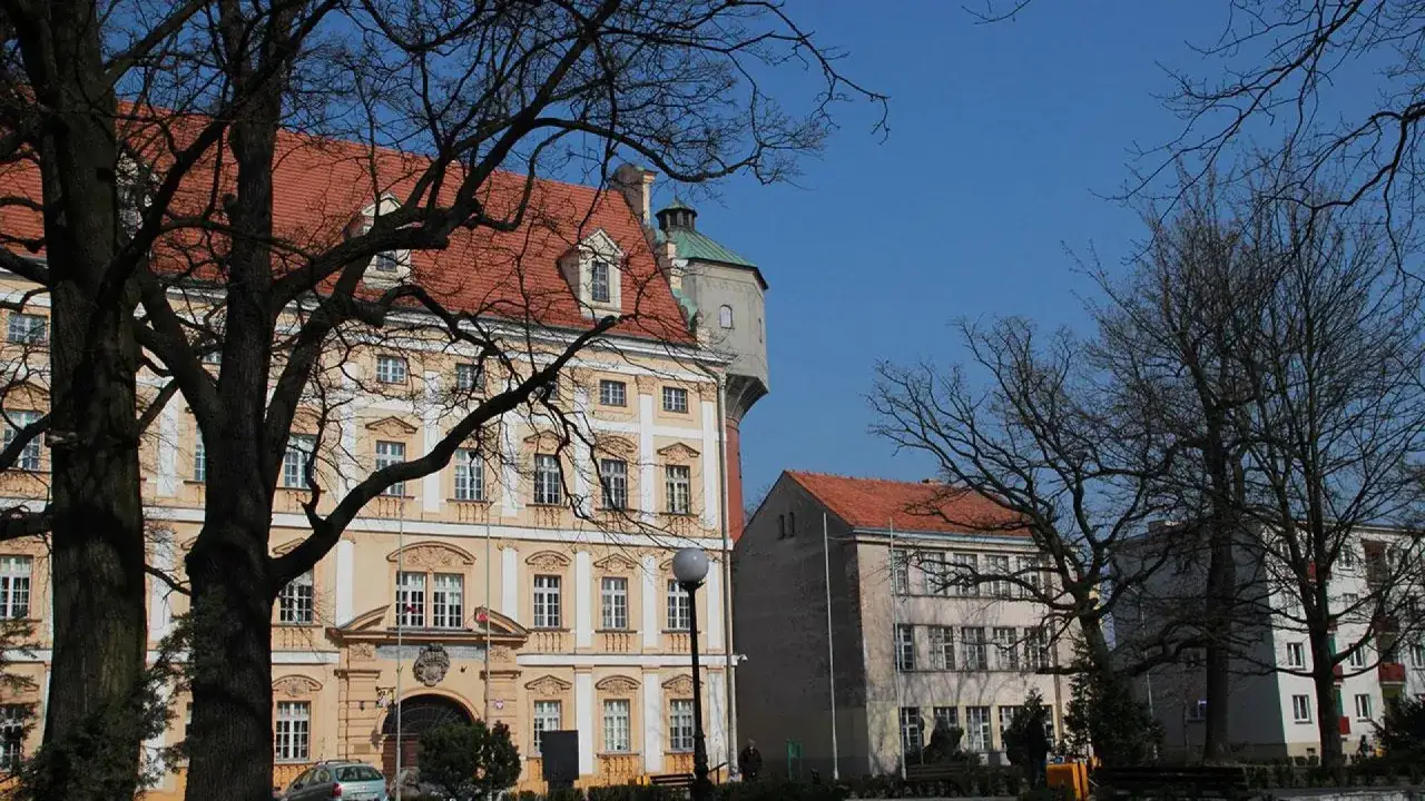 Zamek Piastowski i inne zabytki to miejsca, co zobaczyć w Oławie. Widać tu piękne budynki z czerwonymi dachami i wieżę.