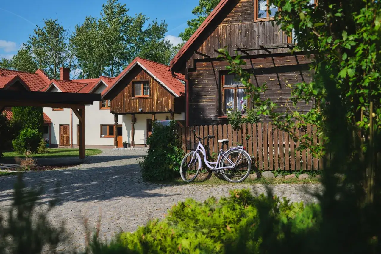 Urocze domki z czerwonymi dachami i drewnianą elewacją, idealne na wypoczynek. Rower czeka na zwiedzanie okolicy. To właśnie takie miejsca oferuje co to jest b&b.