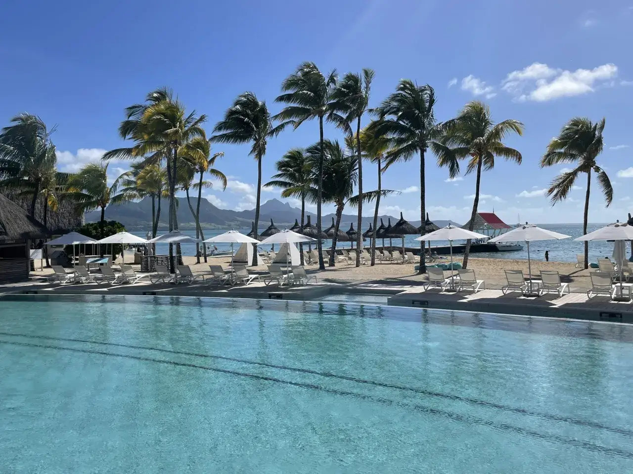 Rajski widok na Mauritius z basenem i palmami. Zastanawiasz się, jaką walutę zabrać na Mauritius? Najlepiej rupie maurytyjskie.