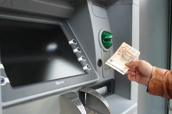 Ręka trzyma banknoty euro przy bankomacie. Tak, w Grecji jest euro.
