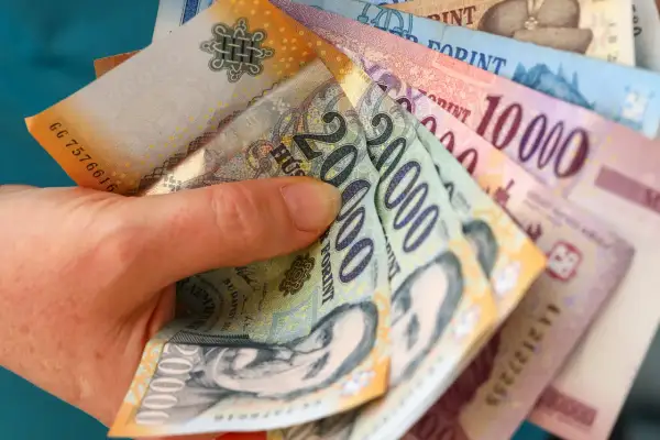 Dłoń trzyma stos węgierskich forintów. Zastanawiasz się, gdzie wymienić forinty? Warto sprawdzić kursy w kantorach lub bankach.