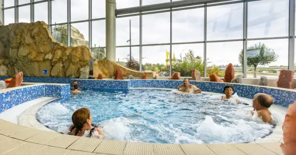 Ludzie relaksują się w jacuzzi. Szukając, które termy są najtańsze, warto sprawdzić oferty z podobnymi atrakcjami.