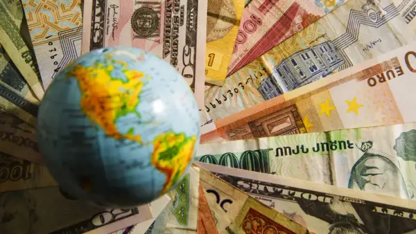 Globus na tle różnych walut. Czy na Malcie można płacić dolarami? To pytanie zadaje sobie wielu podróżnych.